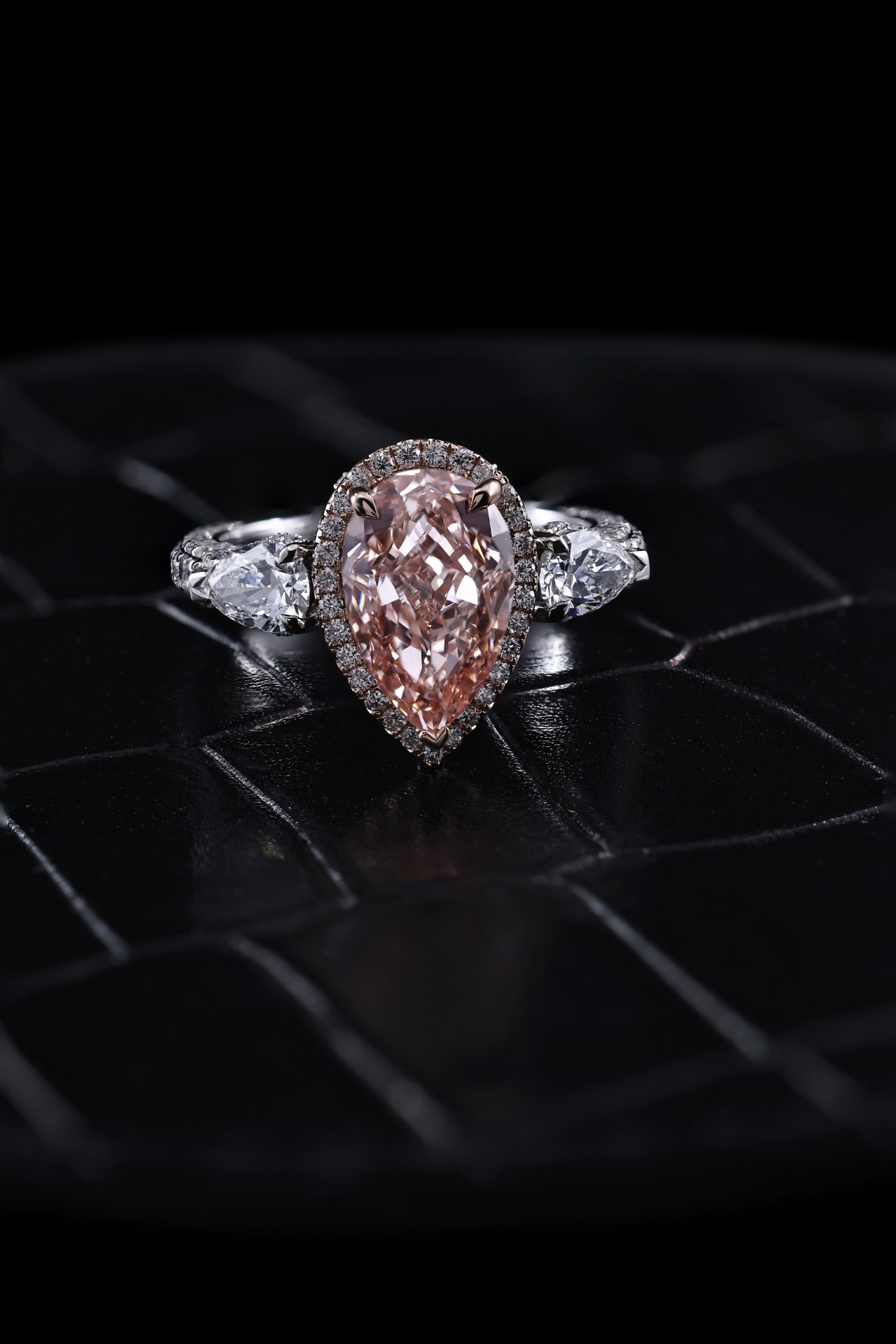 Bespoke pear-shaped pink diamond engagement ring with halo and side stones